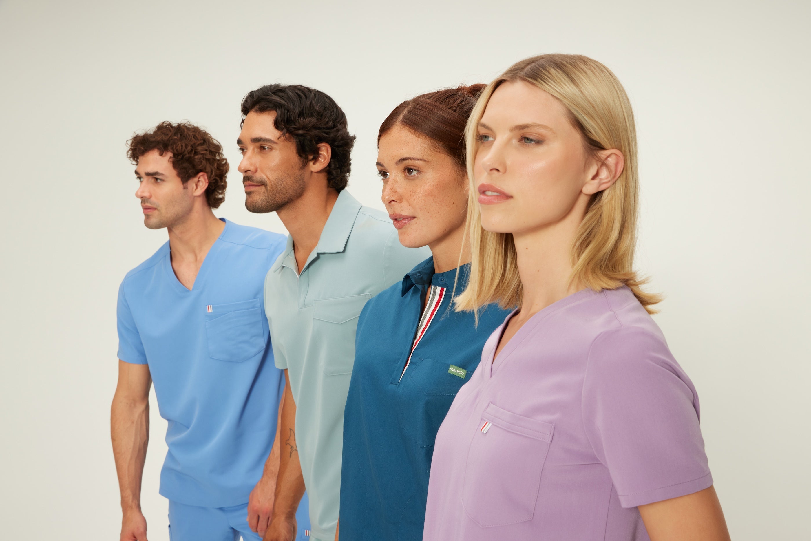 4 nurses wearing scrubs ranging from collared scrub top to jogger scrub pants.