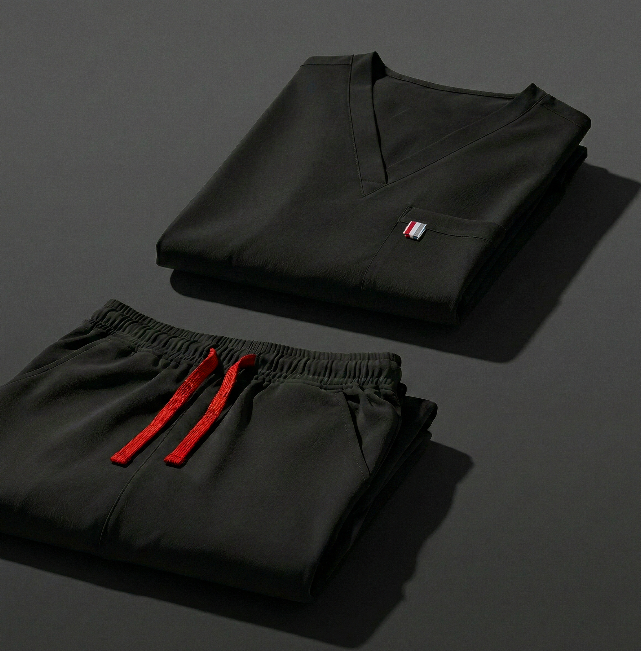 aerial view of black mediclo scrub tops and pants folded neatly on a studio floor.