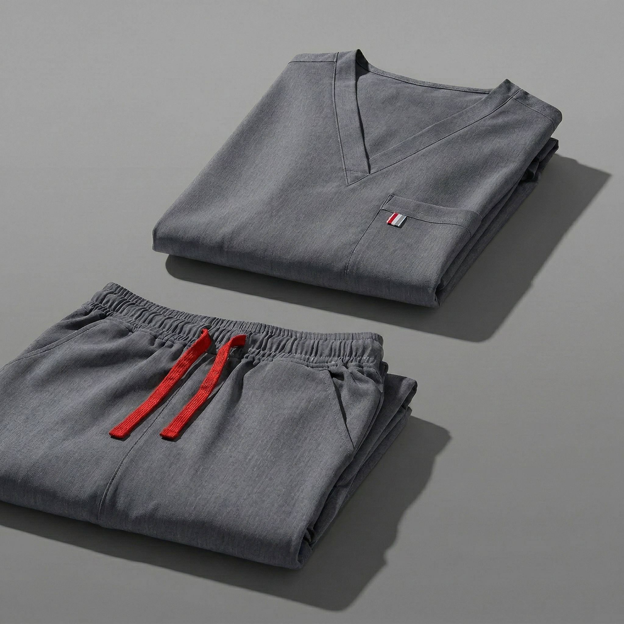 aerial view of heather gray mediclo scrub tops and pants folded neatly on a studio floor.