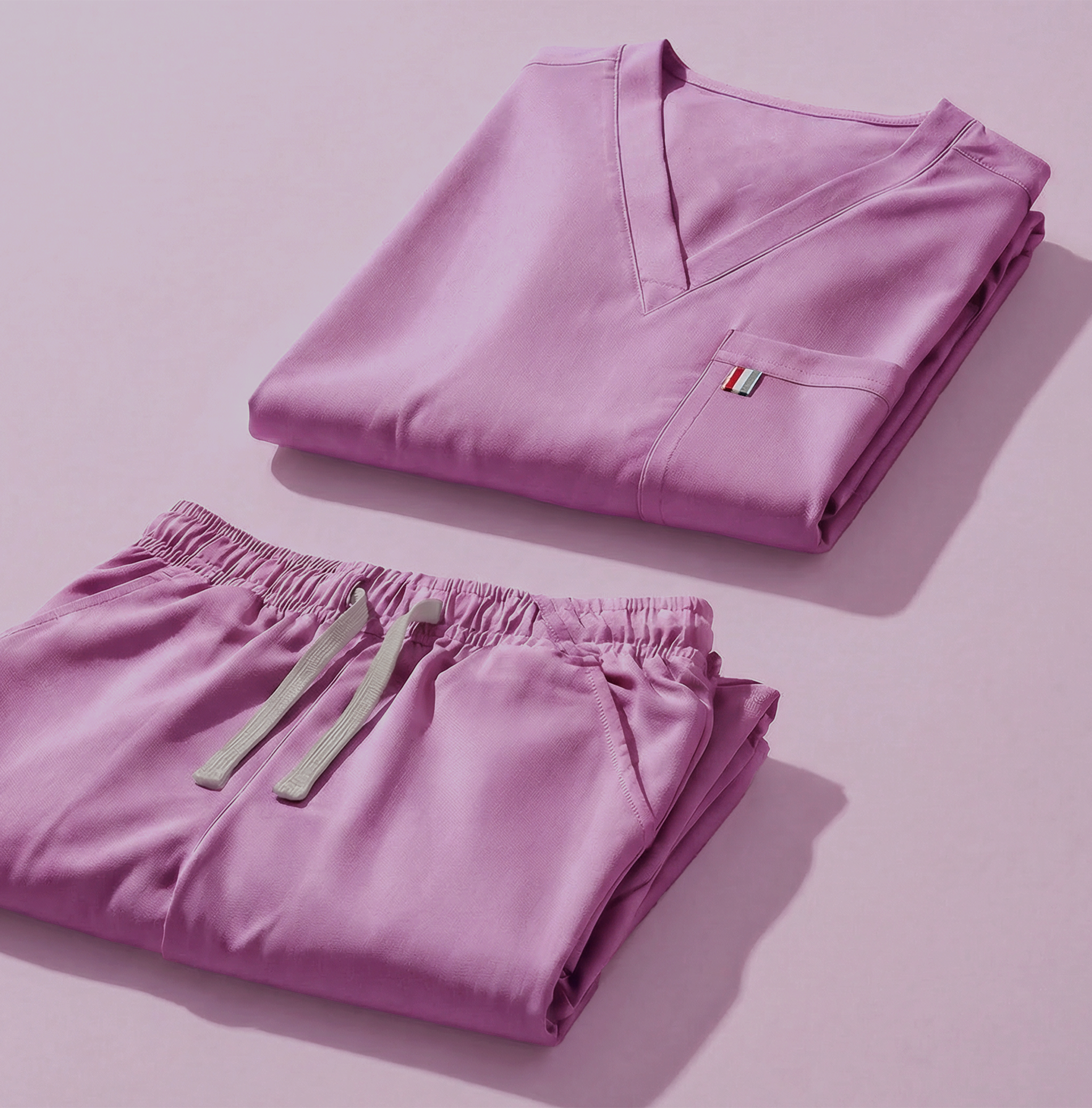 aerial view of lavendar mediclo scrub tops and pants folded neatly on a studio floor.