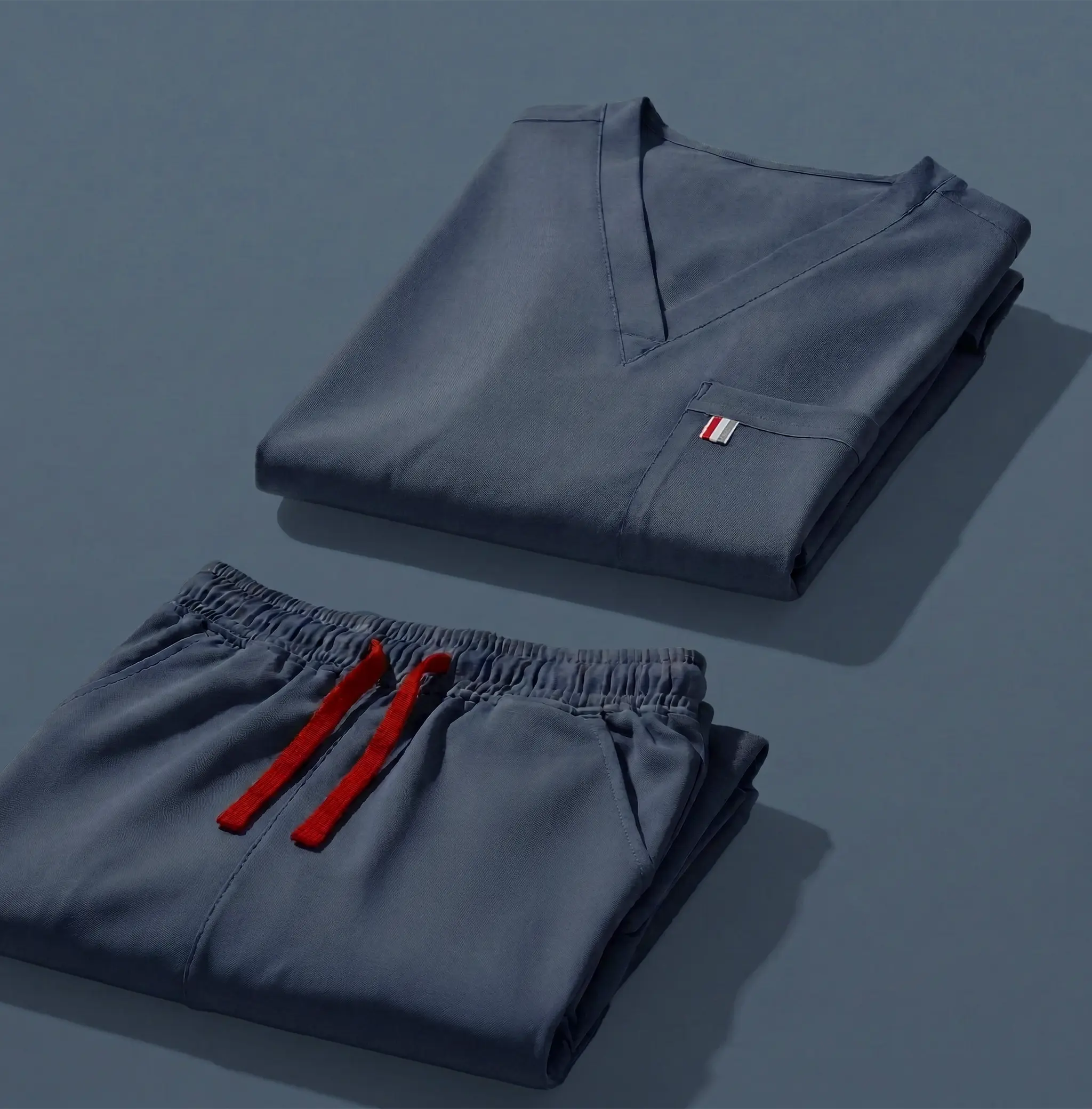 aerial view of moonlight navy mediclo scrub tops and pants folded neatly on a studio floor.