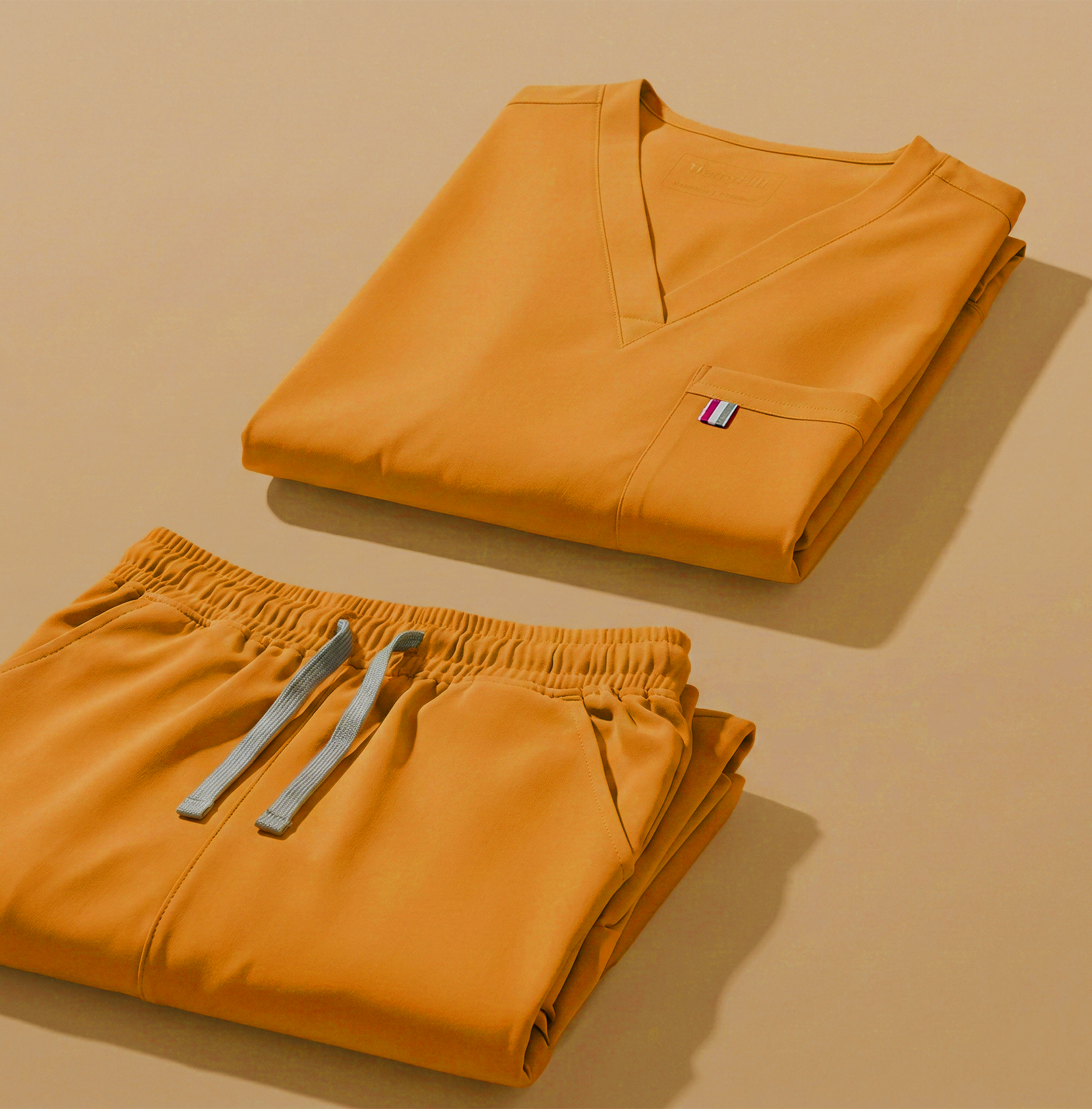 aerial view of sunflower mediclo scrub tops and pants folded neatly on a studio floor.